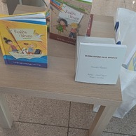 Trzy książki, w tym dwie dla dzieci, stoją na stoliku.