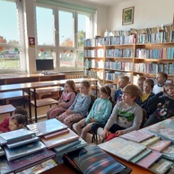 Dzieci w bibliotece oglądają przedstawienie teatrzyku kamishibai.