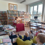 Dzieci oglądają przedstawienie teatrzyku kamishibai w bibliotece.