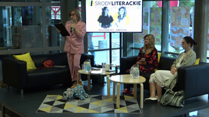 Po lewej prowadząca spotkanie, po prawej, siedzące na kanapie, bohaterki Środy Literackiej, odbywającej się w Galerii Parter, na środku ekran telewizora z plakatem reklamującym spotkanie.